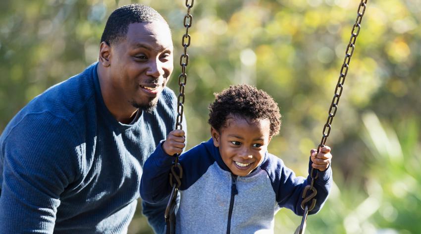 Boy with father, on playground swing