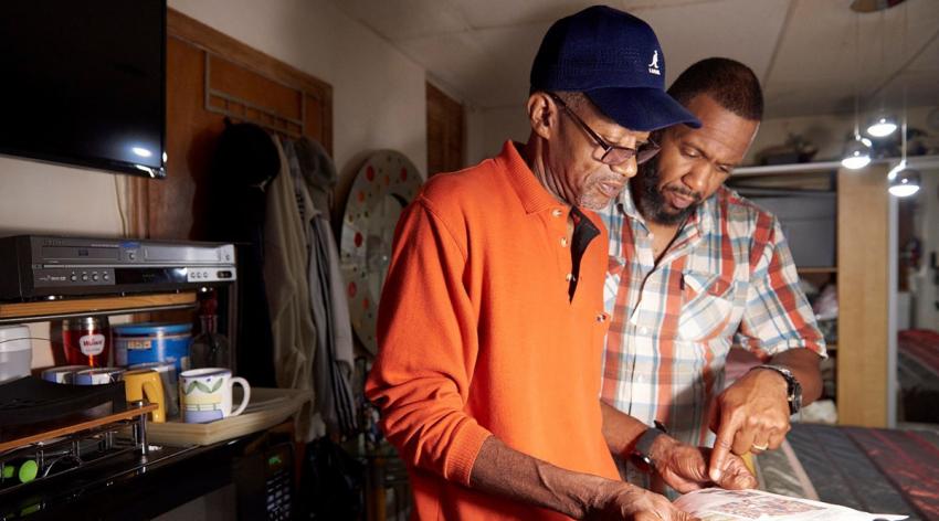 Community health worker Orson Brown (right) reviews health-related goals with a patient during a pre-pandemic home visit in Philadelphia