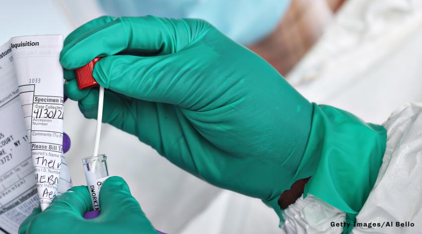 A health care worker sealing a coronavirus swab while holding a filled-out form