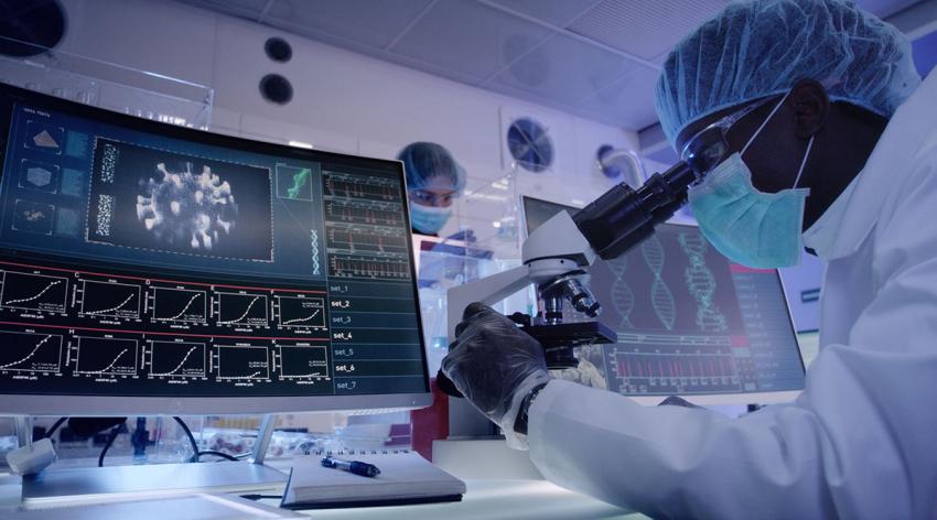 A researcher looks through a microscope in a lab