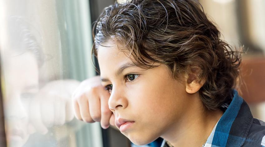 A young child looks out of a window