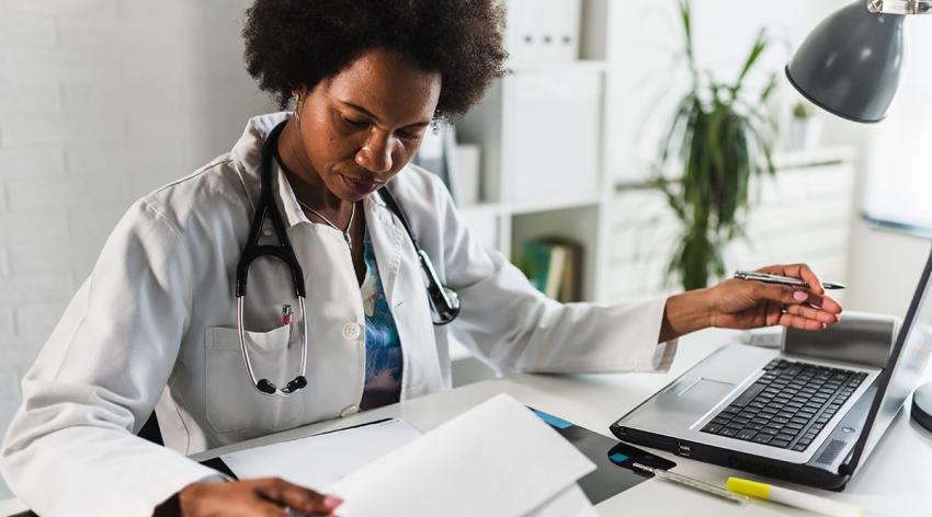 A doctor reviews applications at her desk