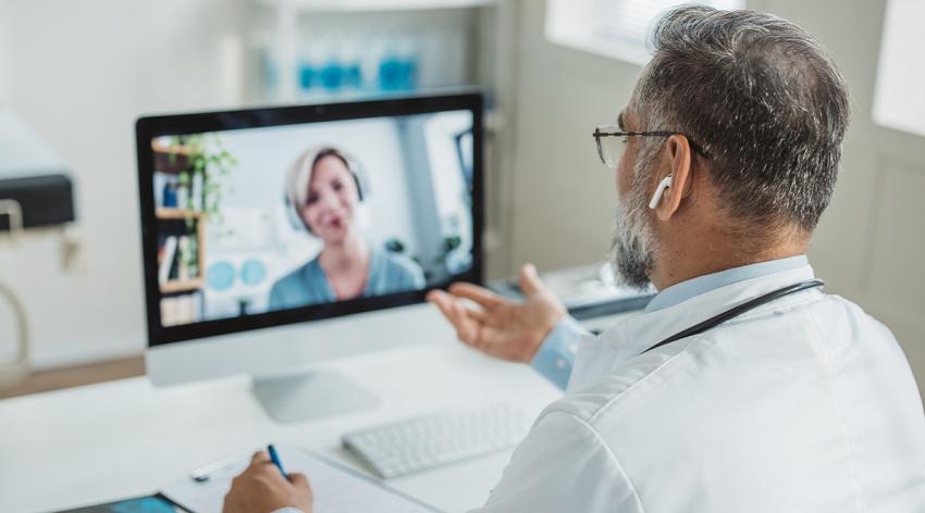 Doctor talking while explaining medical treatment to patient through a video call in the consultation.