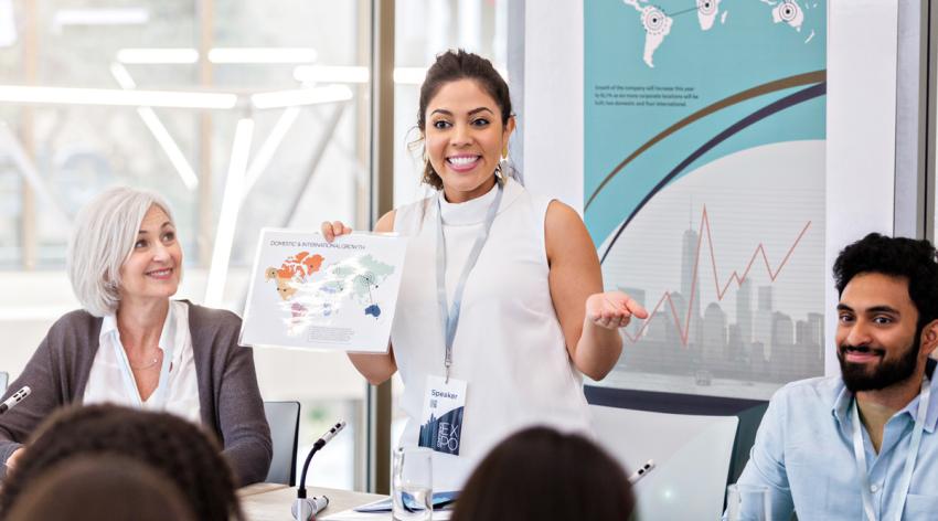 A female facilitator standing and talking at a seminar