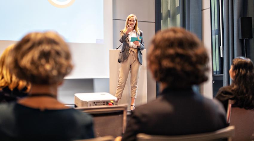 A female facilitator standing and talking at a seminar