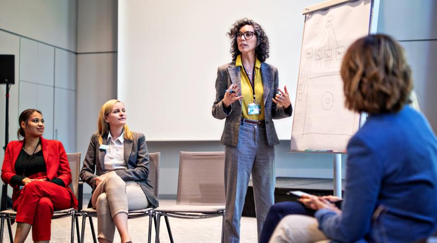 A female facilitator standing in front of a flip chart and explaining her ideas during a seminar.