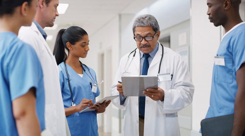 A group of residents listen to a doctor speaking