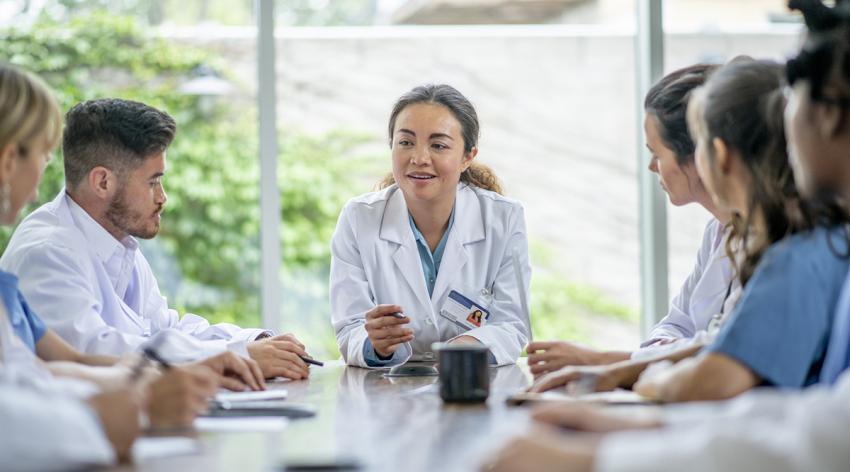 A group of doctors are seated at a table having a conversation