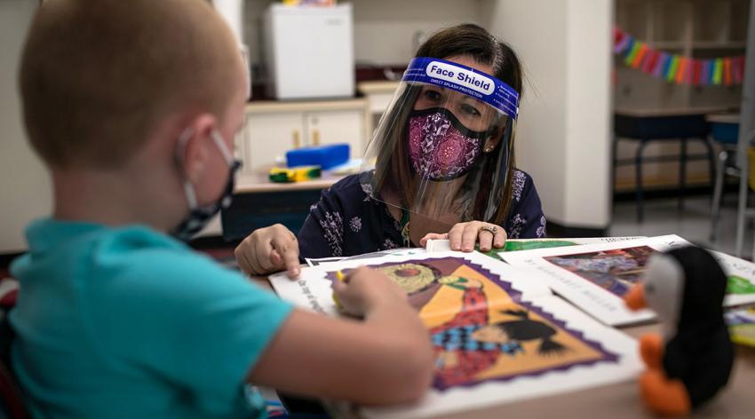 Teacher Elizabeth DeSantis helps a first grader during reading class at Stark Elementary School in Stamford, Connecticut. Most students at Stamford Public Schools attend in-school classes every other day and distance learn the rest.