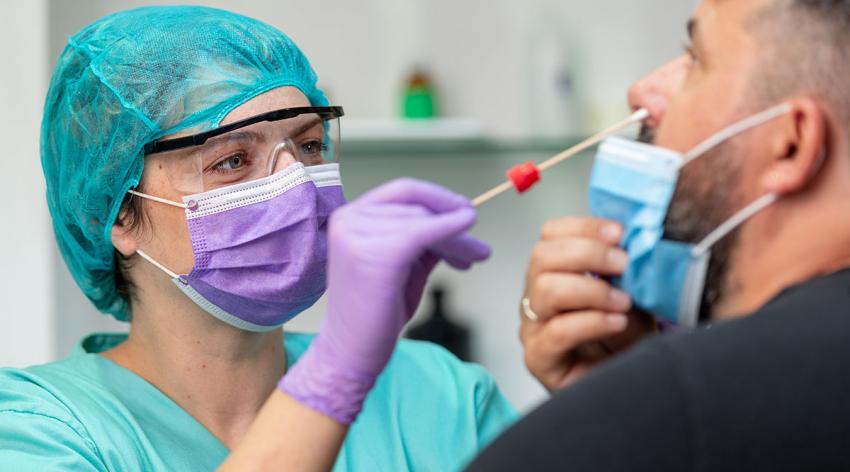 A health care worker administers a COVID-19 test