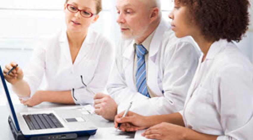 Group of three physicians looking at information on a laptop screen.