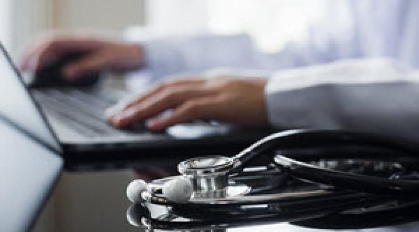 Image of laptop, physician hands, and stethoscope.