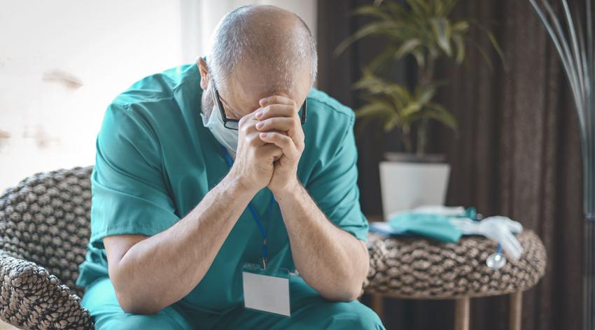 A medical provider rests his head on his hands