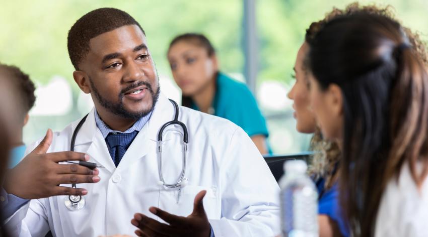 Male doctor gestures as he talks with female colleague while attending a healthcare conference.