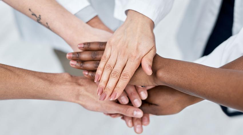 A group of diverse people all touch hands