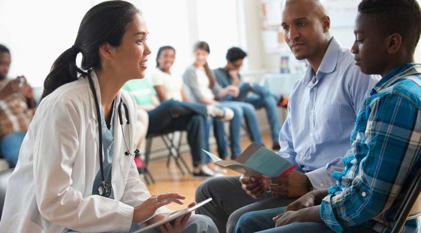 A female doctor talking with a male patient and his guardian