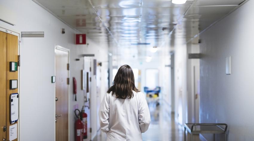 Female doctor walks down a hospital hallway.
