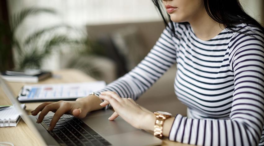 A woman types on a laptop