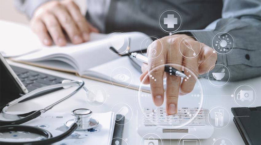 Hand of a doctor using a calculator for medical costs in modern hospital