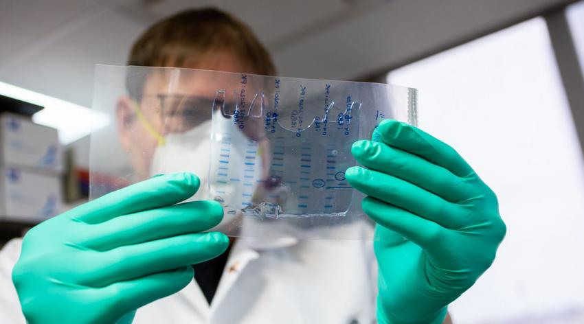 Florian Krammer examines a plastic slide while working in a laboratory.