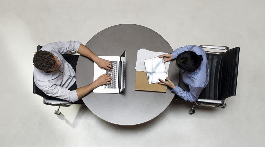 An overhead view of one student using a laptop and one using a tablet