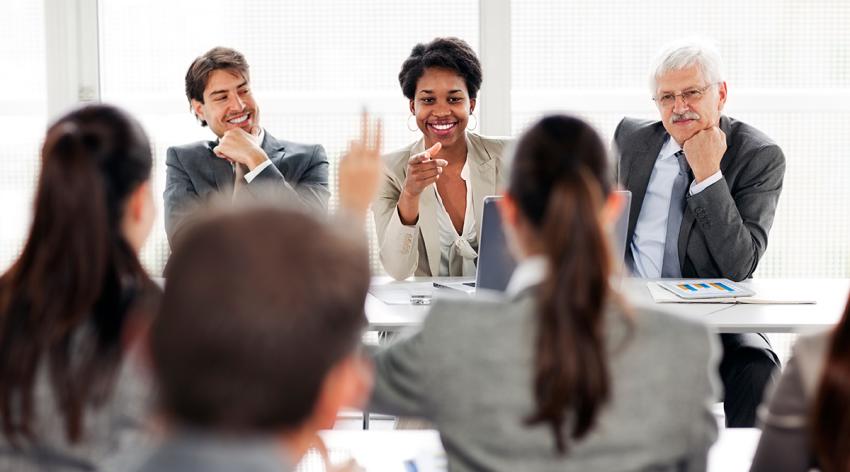 Rear view of business people attending seminar and raising hand