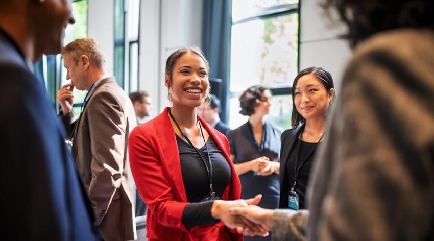 Businesswomen handshaking in auditorium corridor