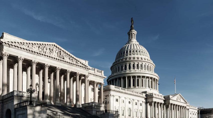 Part of the U.S. Capitol building, framed against a dark blue sky, is seen from the ground.