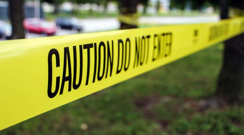 Yellow tape in front of a parking area with the words "Caution Do Not Enter" written on it