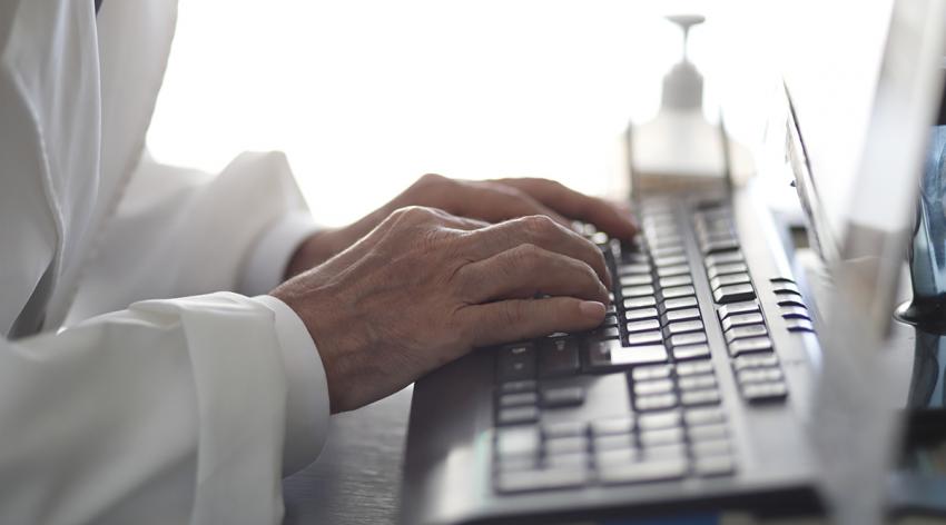A close-up of a doctor's hands at a keyboard
