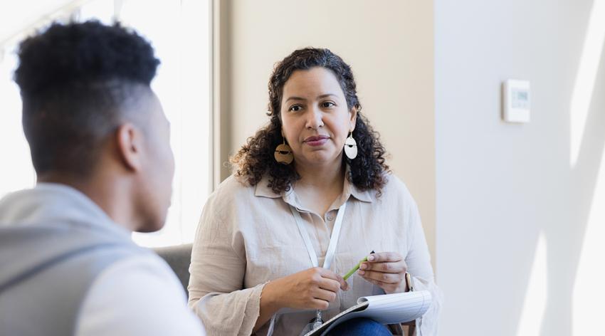 Counselor listens to the young adult and takes notes for their next meeting.