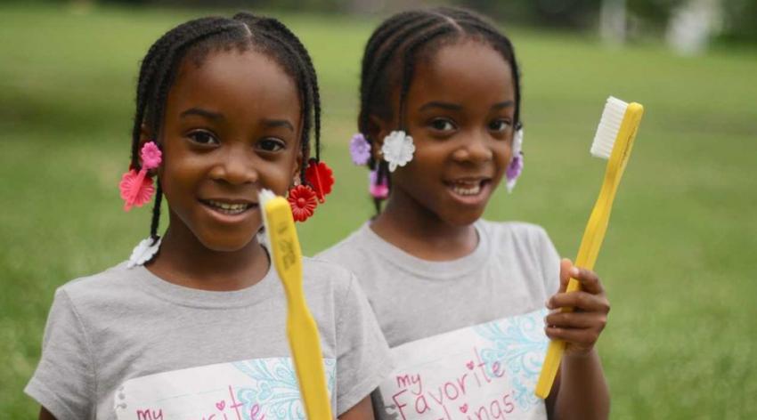 two girls holding big toothbrushes