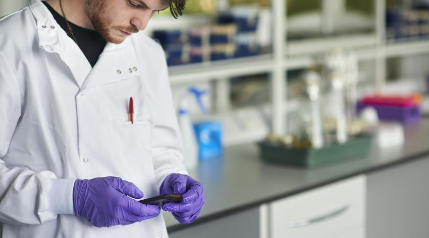 A medical students looks at his cellphone while in a lab.