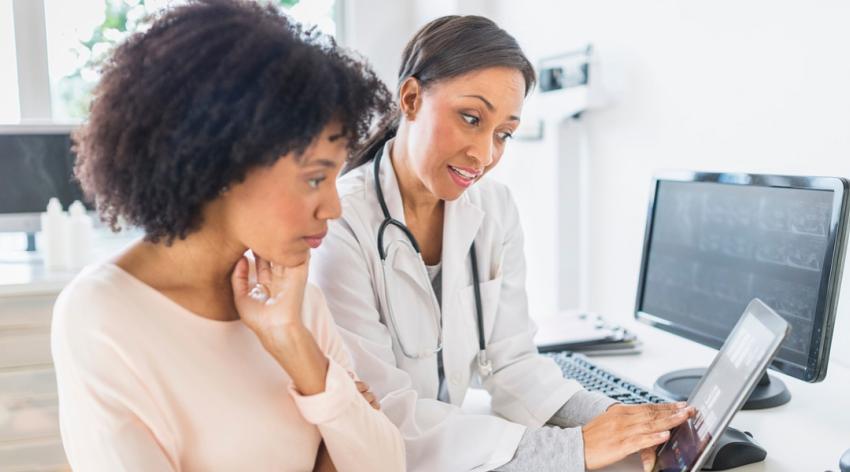 African American doctor and patient talking viewing tablet