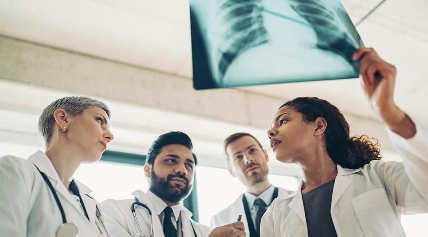 Female doctor showing an x-ray image of man's lungs to her colleagues