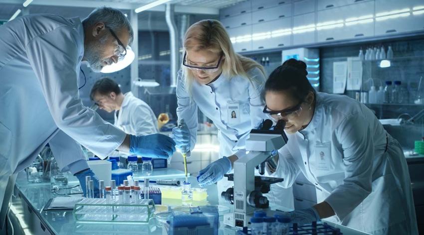 Doctors in blue lab coats work together in a lab