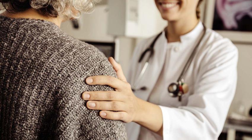 Woman doctor comforts an older patient