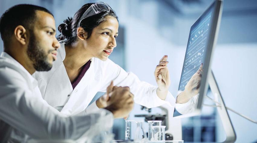 A male  researcher and a female researcher look at a flat screen computer monitor