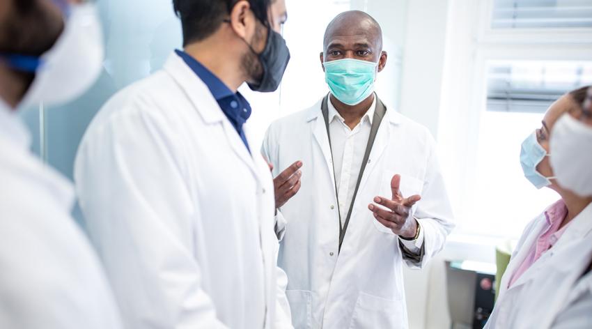 A small group of doctors wearing masks having a conversation in a hospital