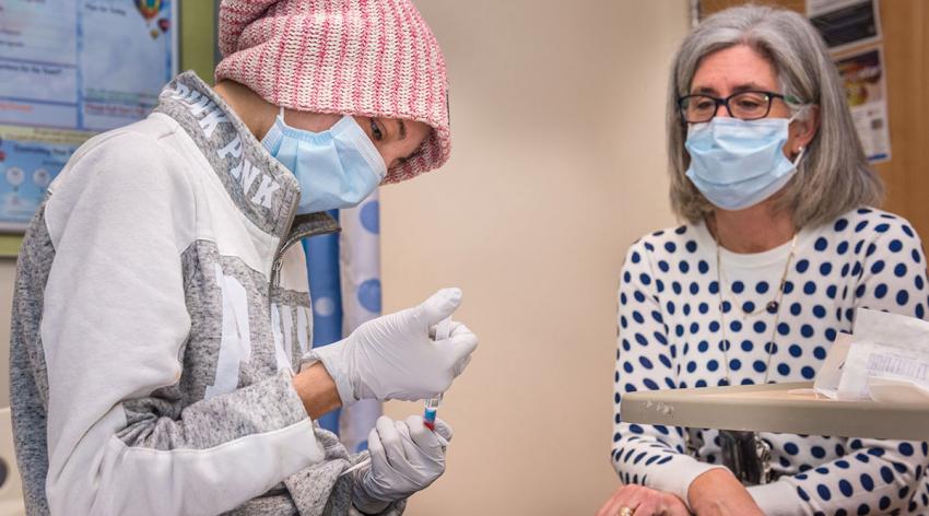 A young woman demonstrates her central line care skills in a training program for parents and teenage patients.