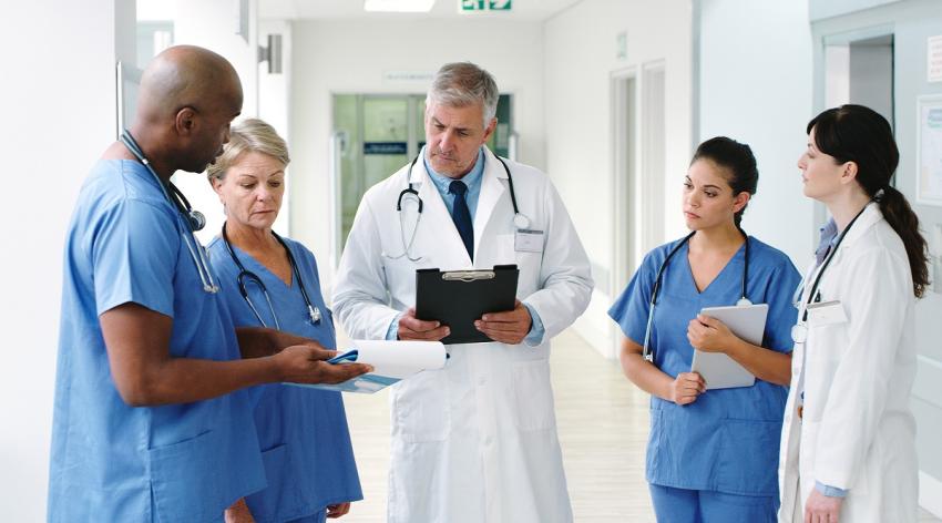 Shot of a male nurse discussing his notes with his team of medical colleagues