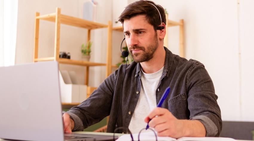 Young man working remotely with laptop and headphones