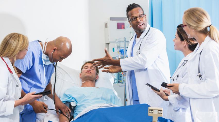 A doctor discussing the patient's illness or injury with the residents.