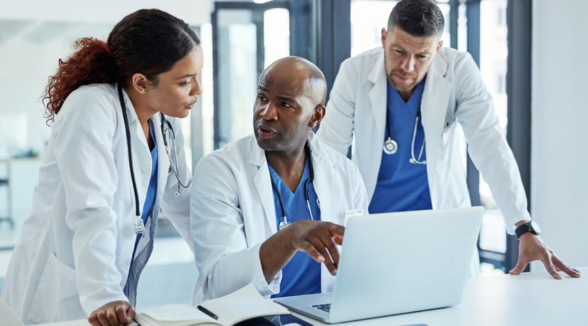 A group of medical practitioners working on a laptop together