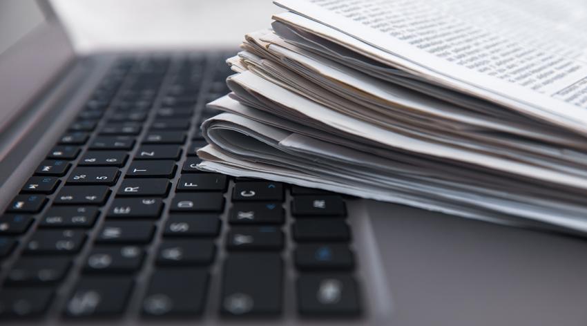 Pile of daily newspapers on a computer