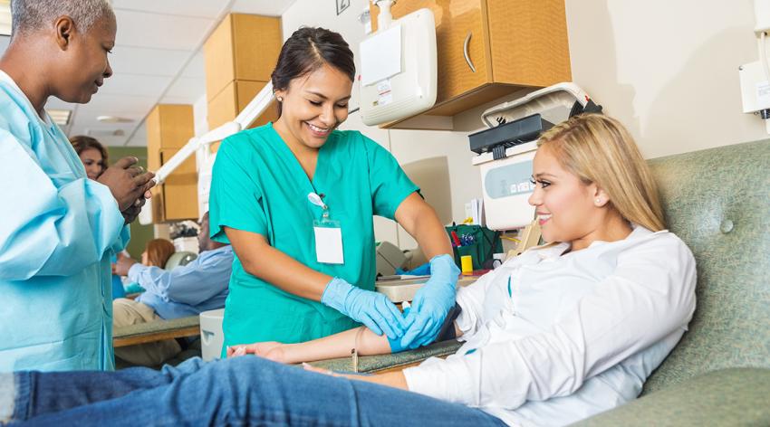 Nurse in blood donation center training someone to insert line