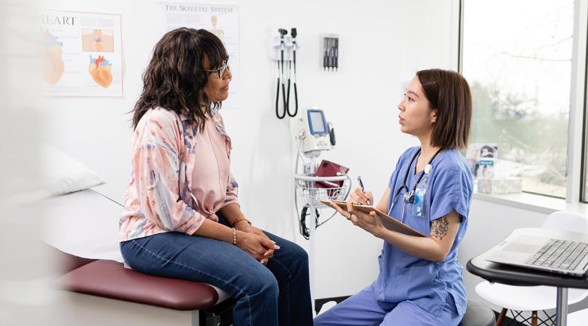 Female nurse makes notes while talking with the patient