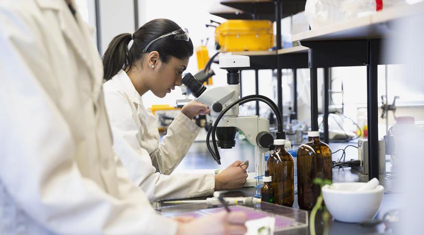 a woman looking in on a microscope