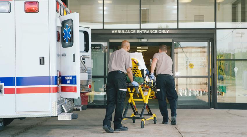 Paramedics taking patient on stretcher from ambulance to hospital