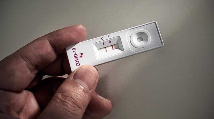 Close-up of adult hand holding a positive result COVID-19 or SARS CoV-2 test kit with result